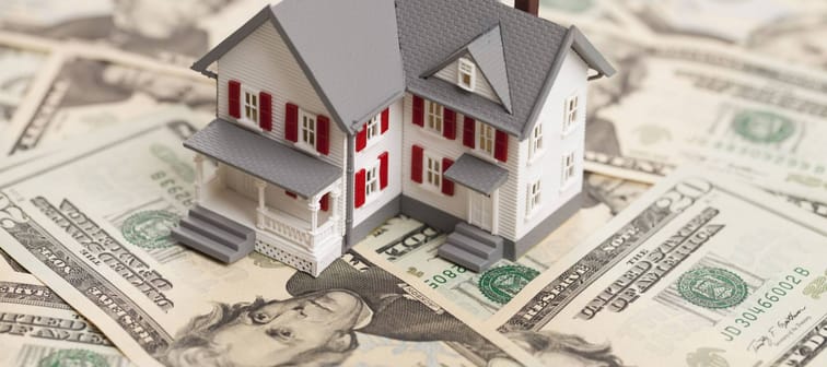 Single family house on pile of money. Concept of real estate.